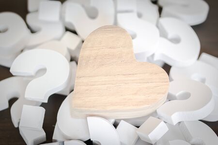 Wooden Heart over group of White Question mark , Problem concept
