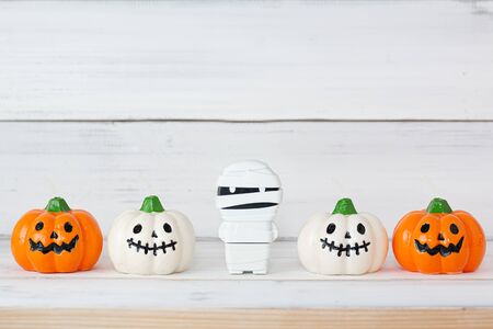 White and Orange candle pumpkin with mummy on white wooden background with copy space.の写真素材