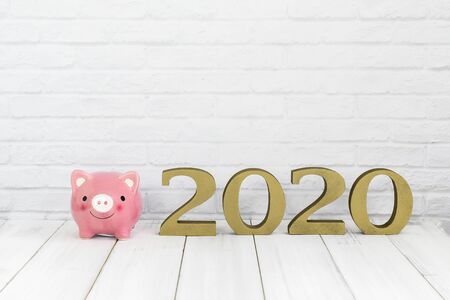 2020 new year and  piggy bank on white wood table over white background with copy space , saving conceptの写真素材