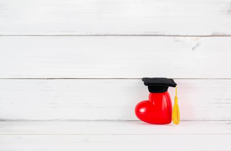 Red Heart with Graduation Cap on white wood background. Successful Love and Relationship Concept with copy space.の写真素材
