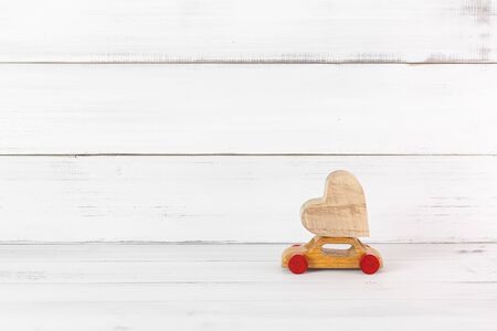 Wooden Heart on Wooden Toy Car on white wood background. Love Travel Concept with Copy Space.の写真素材