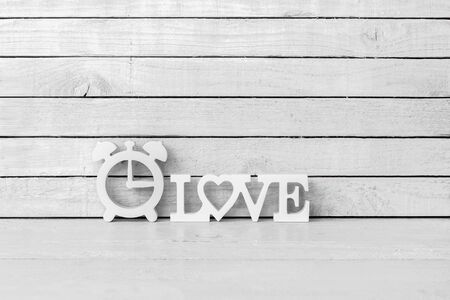 Clock Shaped with Love Alphabet on white wood over white wood backgroundの写真素材