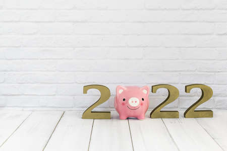 2022 new year and  piggy bank on white wood table over white background with copy space , saving conceptの写真素材