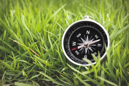 Black Compass on Lush Green Grass Signifying Guidance and Directionの写真素材