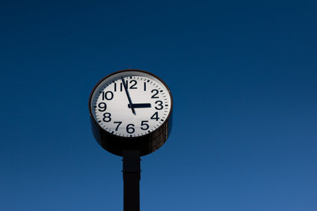 Classic Clock Tower Against Clear Blue Sky at Noonの写真素材