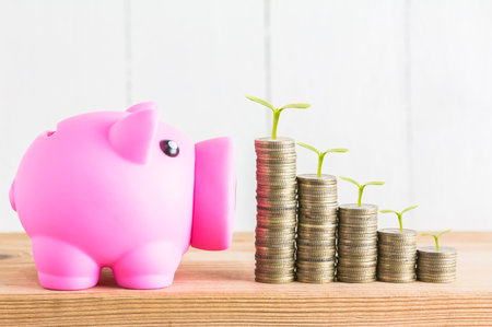 Building Wealth: Pink Piggy Bank and Coins Representing Financial Growthの写真素材