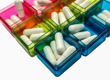 Many white capsule are filled in various color pill boxの写真素材