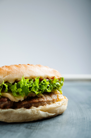 Delicious juicy burger with grilled meat, salad and chees on gray teable, vertical imageの写真素材