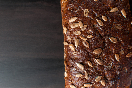 delicious fresh baked bread with bran sunflower seeds on a dark table photographed from above,...