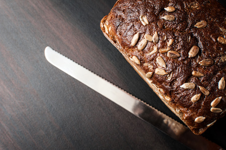 fresh delicious baked bread and knife on a dark kitchen table, horizontal image