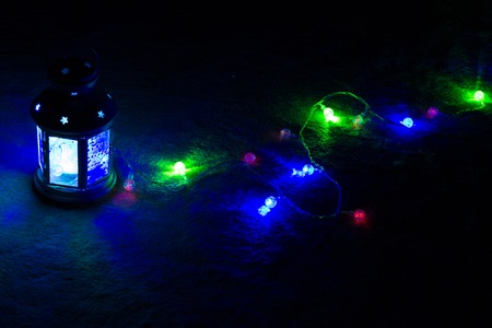Holiday Greeting Card or Background. Christmas Lights and Candle Lantern on Dark Background....