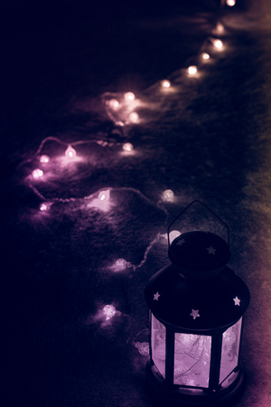 Holiday Greeting Card or Background. Christmas Lights and Candle Lantern on Dark Background. Christmas at Home. New Year Holiday Template.の写真素材