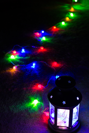 Holiday Greeting Card or Background. Christmas Lights and Candle Lantern on Dark Background. Christmas at Home. New Year Holiday Template.の写真素材