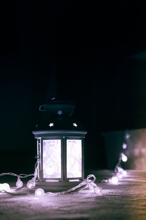 Holiday Greeting Card or Background. Christmas Lights and Candle Lantern on Dark Background....