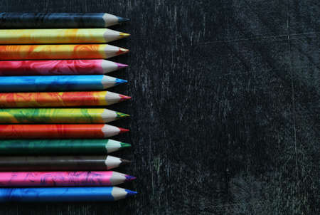 Bright colored pencils on dark background. Blackboard and educational tools. Back to school mockup with copy space.の写真素材