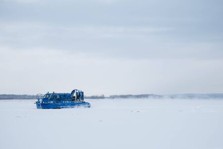 A transport blue airbag rushes along the frozen ice of the Volga River. Behind her rises from the...