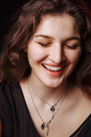 The young brunette laughs cheerfully. Eyes girl closed. High quality photoの写真素材