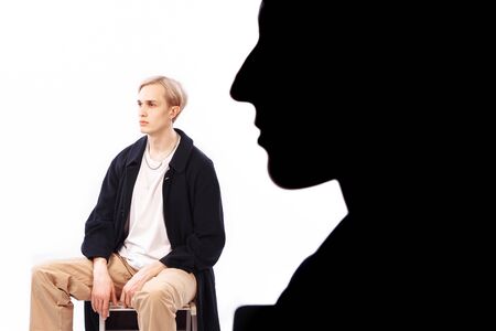 Silhouette of a woman's profile. A man is sitting on a chair. Both look in the same direction. Photo...