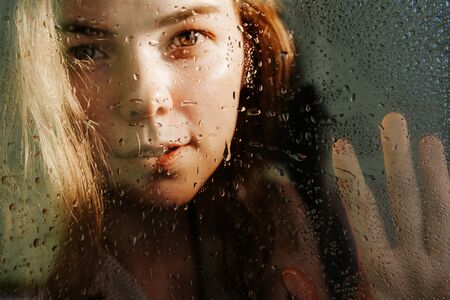 A girls palm is pressed to the glass.の写真素材