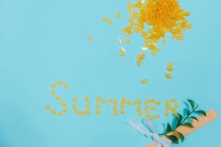 The inscription Summer is lined with pieces of wax for depilation. In the right ug, pieces of wax are scattered in the shape of the sun. In the right needed coal lies a spatula for depilation.の写真素材