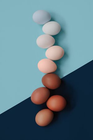 Different eggs in shape and color. A lot of eggs are on the blue table. The table is divided into 2 parts with different colors: dark and light.の写真素材