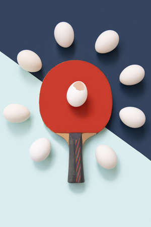 The red racket is in the center. There is a broken egg on the racket. There are whole eggs lying...