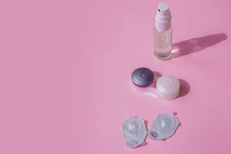 Contact lens kit. The pink table is a spray for disinfecting hands, a container for the lenses and blisters with contact lenses. The lid containers are signed left and right.の写真素材