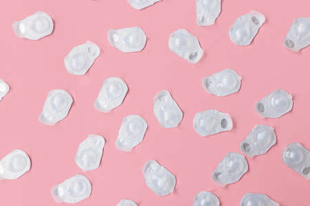 A lot of blisters with contact lenses interspersed on a pink background. Blisters are new and not open. Suitable for postcards, packaging paper and other purposes.の写真素材