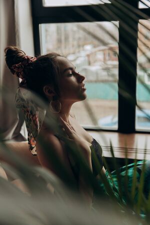 A beautiful brunette is sitting opposite the window.の写真素材