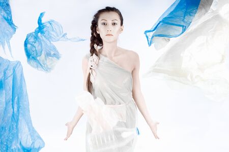 Garbage bags are flying at the girl in the trash bag. The girls hair is braided. Multicolored packages fly in the air. A milk bottle flies past the girl.の写真素材