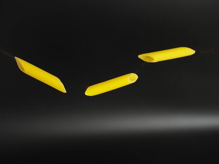 Flying pasta over black background, not cookedの写真素材