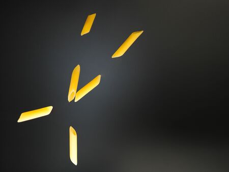 cross of flying pasta and black background, not cookedの写真素材