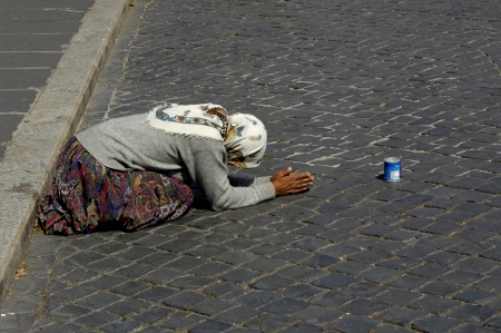 an romani homeless person who beg on a paved road in Franceの写真素材