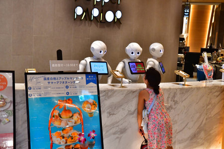 Tokyo; Japan - August 10 2024: a young girl speaks to robots in a bar restaurant in the Shibuya...