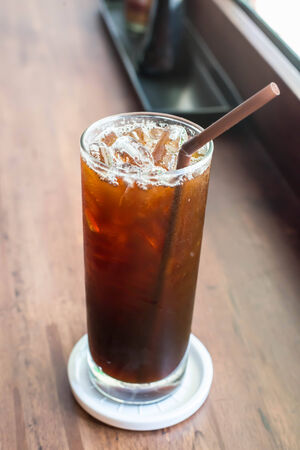 Iced black coffee on the wooden table in coffee cafe.の写真素材