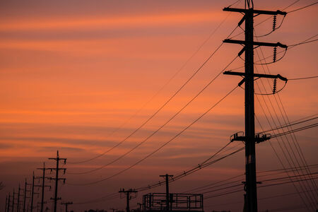 Electricity cable communication towers on sunset stretching across the river.