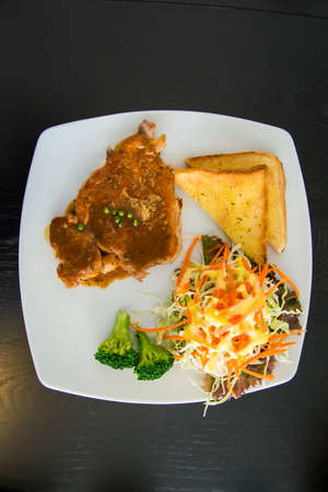 Pork steak with toast on a wooden table.