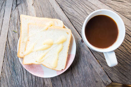 Cup of coffee and a slice of bread on a wooden table.の写真素材
