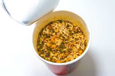 cooked instant cup noodle with ingredient on white backgroundの写真素材