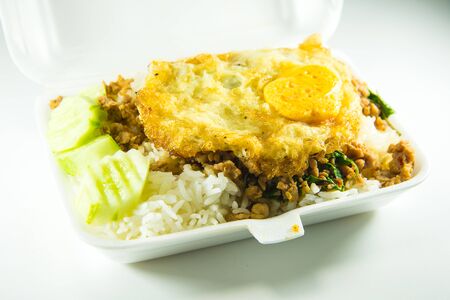 Rice topped with stir-fried pork and basil in a foam boxの写真素材
