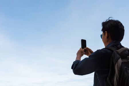 A man is using mobile phones to take pictures and blue sky