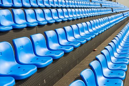 Blue seats on the grandstand of the football stadium.の写真素材