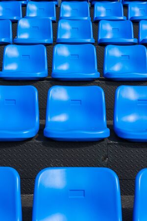 Blue seats on the grandstand of the football stadium.の写真素材