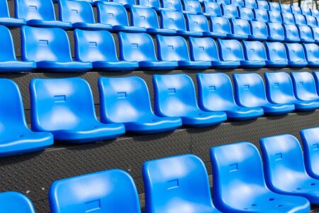 Blue seats on the grandstand of the football stadium.の写真素材