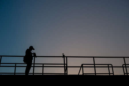 Silhouette of professional photographer taking photo of beautiful sunsetの写真素材