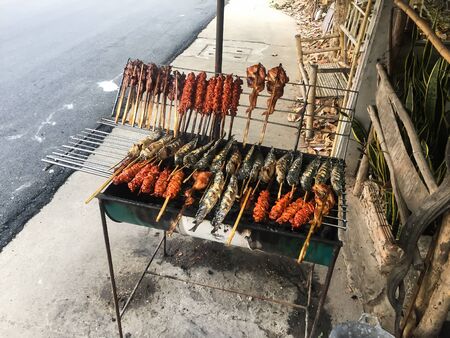 Chicken and fish grilled on a metal grill with smoke.Thailand country food.の写真素材
