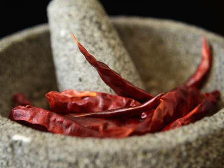 close up of mexican molcajete, kitchen mortar and dry chile, mexican molcajete to make salsa with chile, chile de arbol dry, ingredients for spicy salsa, mexican chile,の写真素材
