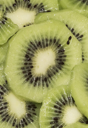 Actinidia deliciosa kiwi cut into slices with honey on top, green vegetarian dessert with radially located seeds flash lightingの写真素材