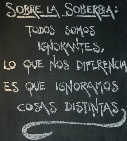 Chinese proverb about the arrogance and ignorance written in chalk on a blackboard in Spanishの写真素材