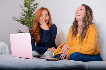 two colleagues laugh during a day of teleworkingの写真素材